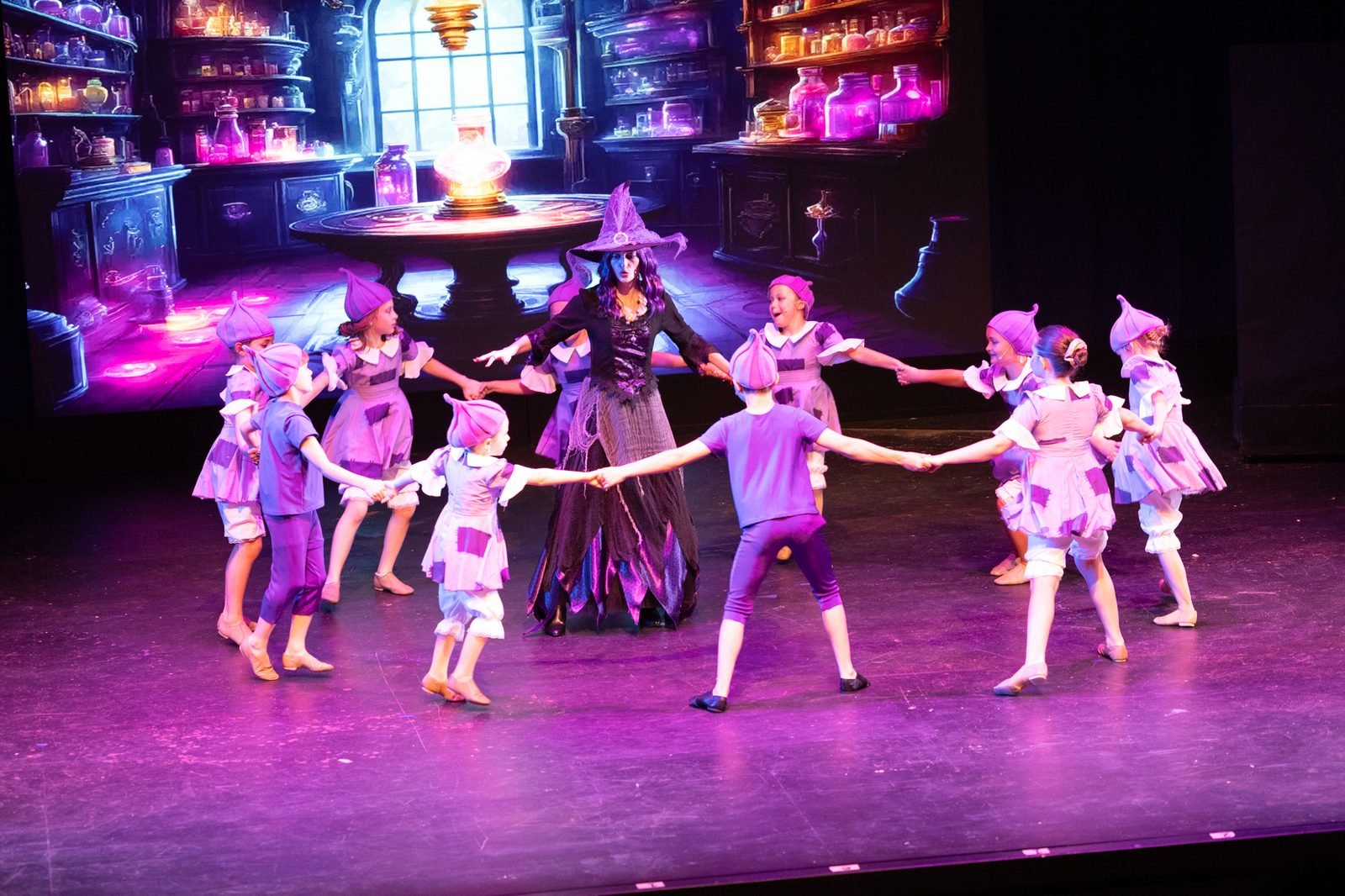 Young Bravo dancers in purple costumes dancing in a circle on stage